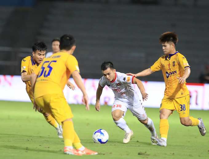 Hoàng Nam trong vòng vây của các cầu thủ SLNA - Ảnh: Phan Tùng 